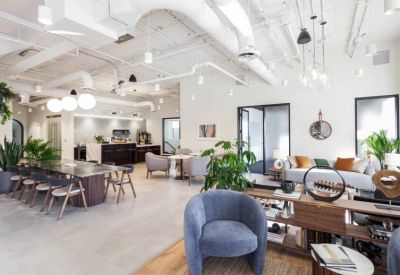 Spacious communal lounge with a large marble table, modern seating, and industrial ceiling details.