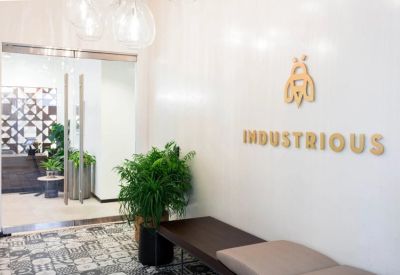 Reception area featuring a minimalist wood bench and a golden company logo on the wall.