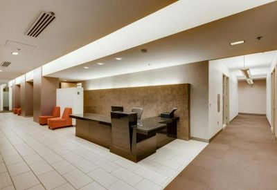 Professional reception desk with a dark stone counter and orange accent armchairs.