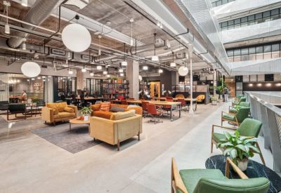 Spacious communal lounge with industrial ceilings, plush seating, and tiered office levels.