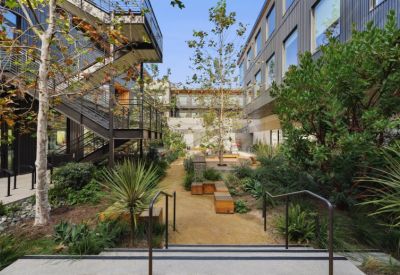 Lushly landscaped courtyard with wooden seating and stairs.