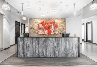 Minimalist reception desk with a textured grey facade and large abstract red art piece.