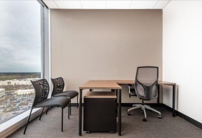 Private corner office featuring an L-shaped wooden desk and floor-to-ceiling windows.