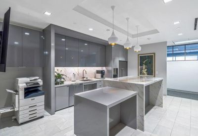 Modern communal kitchen and breakroom with sleek gray cabinetry and marble islands.