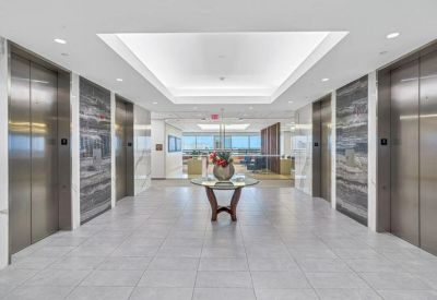 Bright elevator lobby with marble floors and a decorative center table.