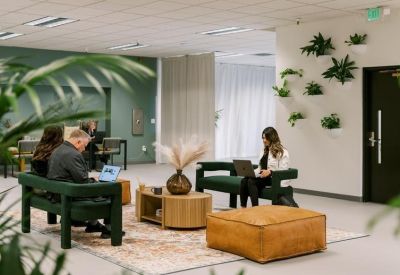Casual breakout area with green velvet benches and a wall decorated with small plants.