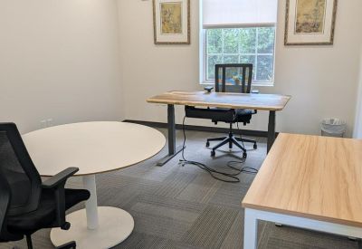 Spacious private office with a round meeting table, two workstations, and ample natural light at 4301, 50th Street Northwest.
