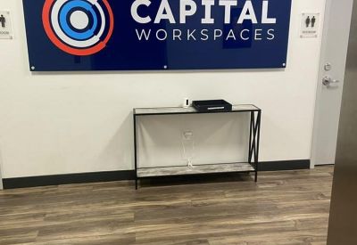 Reception area featuring a blue branded Capital Workspaces sign above a modern console table.