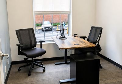 Two-person private office with a height-adjustable wooden desk and window view.