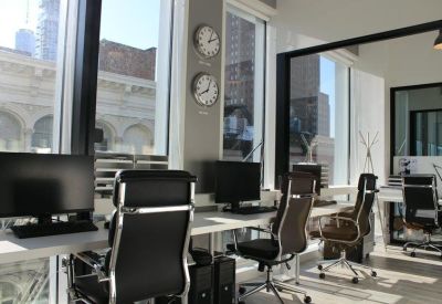Professional row of desks with black executive chairs and world clocks.