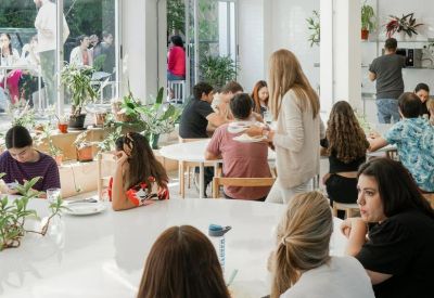 Bright communal dining and coworking area with plants and unique zigzag lighting.