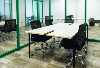 Modern meeting room with green glass partitions and ergonomic black chairs.