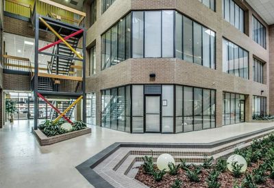 Multi-story building lobby with an industrial steel staircase and a brick-stepped garden feature.
