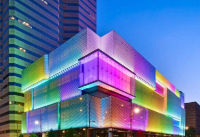 Modern building exterior illuminated with vibrant colorful LED lights at night.