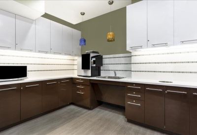 Modern communal kitchen area with dark wood cabinetry and white upper cupboards.