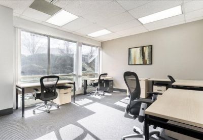 Bright open-plan office space with four workstations and large windows.