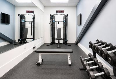 Compact fitness center with a weight bench, cable machine, and dumbbells.