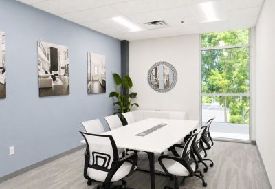 Bright conference room with a long white table, ergonomic chairs, and large windows.