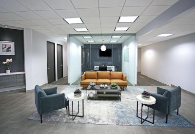 Lounge area featuring a tan leather sofa and blue armchairs on a patterned rug.