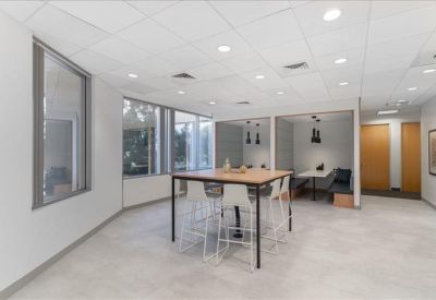 Spacious open-plan lounge area with grey armchairs and natural light.