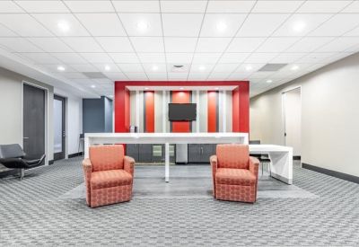 Communal breakout area featuring red accent walls and orange armchairs.