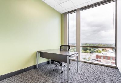 Private windowed office with a grey desk and city views.