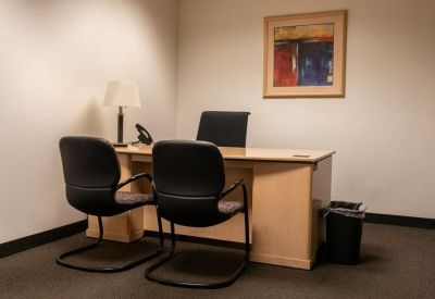 Private office featuring a wooden desk, guest chairs, and framed artwork.