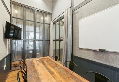 Small meeting room with a rustic wood table, whiteboard, and glass partition.