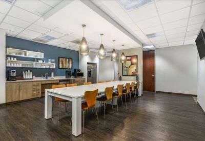 Communal kitchen area with long white dining table and stylish pendant lighting.