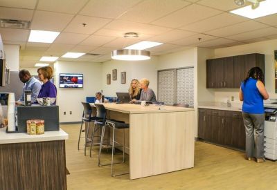 Communal kitchen and break area with a central high-top table and seating.