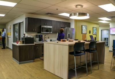 Modern office kitchen with dark cabinetry, microwave, and coffee station.