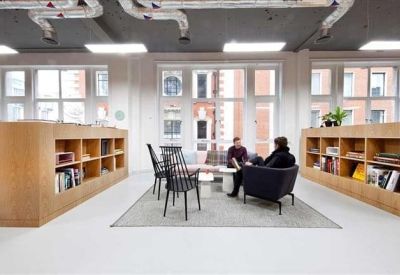 Open-plan office space featuring wooden shelving units and large windows.