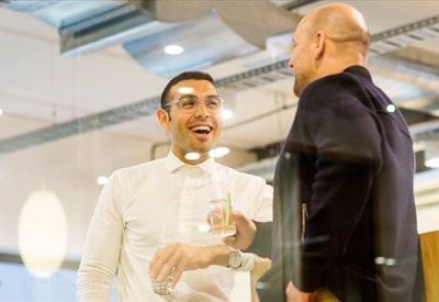 Two professionals engaging in a casual conversation within a bright, open breakout area.