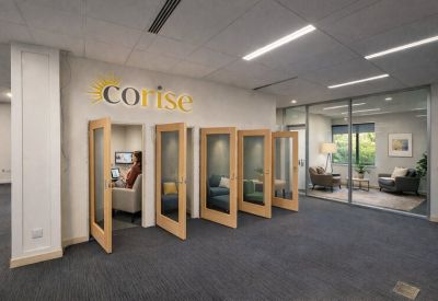 Hallway featuring four glass-fronted private work pods with ergonomic seating inside.