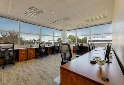 Open-plan office with multiple desks and large windows.