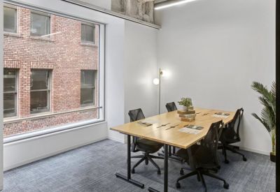 Modern conference room with a light wood table and view of a brick building.