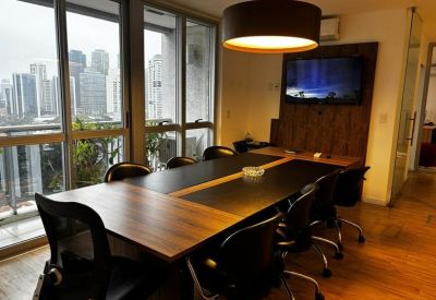 Professional meeting room with a large table, mesh chairs, and a wall-mounted TV.