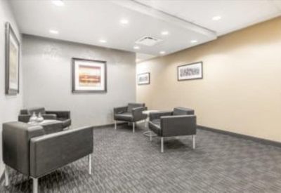 Professional lounge area with charcoal grey armchairs and framed wall art.
