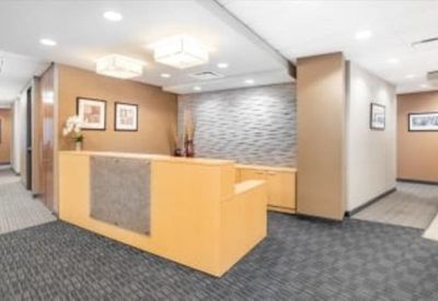 Reception area featuring a warm wooden front desk, patterned carpet, and decorative textured feature wall.