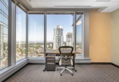 Bright private office featuring a mesh task chair and large windows overlooking high-rise buildings.