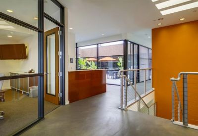 Bright lobby featuring an orange accent wall, glass partitions, and a wooden reception desk.