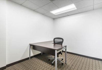 Private office suite featuring an L-shaped dark wood desk and ergonomic chair.