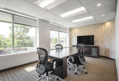 Modern conference room with a large wooden table and wall-mounted screen.