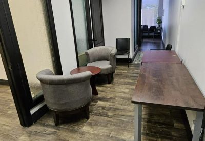 Lounge area with comfortable grey armchairs and a long wooden work table.