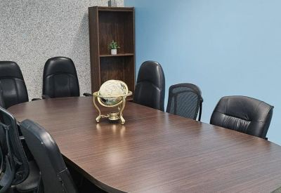 Conference room with a large oval wood table and high-back leather chairs.