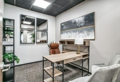 Private office featuring a wooden desk, leather chair, and decorative wall mirrors.