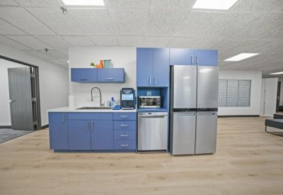 Kitchenette with blue cabinets, stainless steel refrigerator, and modern appliances.