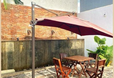 Outdoor communal terrace with a red umbrella, wooden table and chairs, and a brick feature wall.
