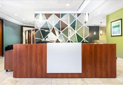 Modern reception area with wooden desk and geometric mirror design.
