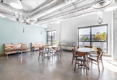 Spacious communal lounge with industrial ductwork and circular tables.